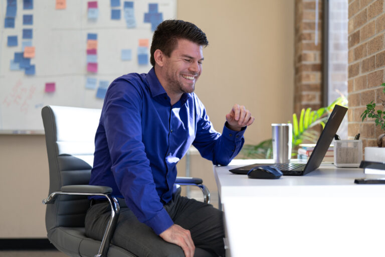 A LeanDNA worker smiles at their laptop in the office